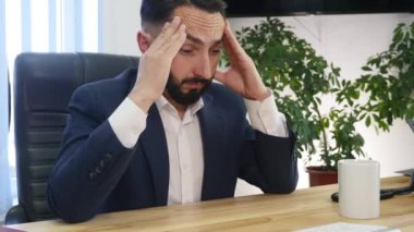 Genç işadamı ofiste çalışmalar sırasında baş ağrısına sahip