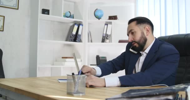 Jonge zakenman aan de telefoon bij office — Stockvideo