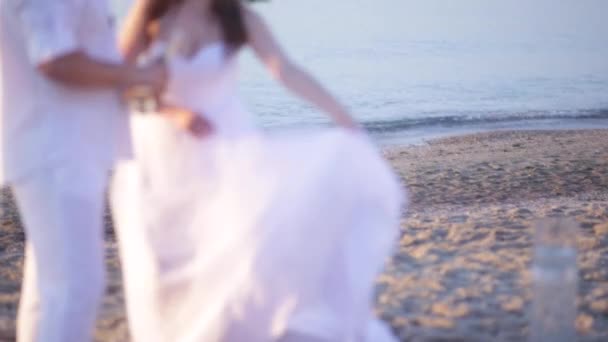 Novomanželé na pláži při západu slunce není v centru pozornosti — Stock video
