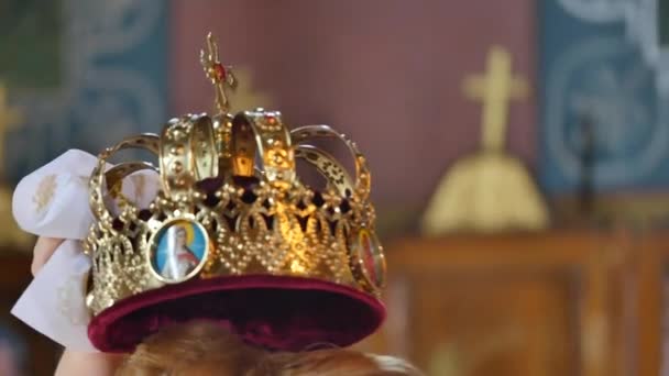 Ceremonia de boda novia y novio en la Iglesia Ortodoxa. Testigos sostienen coronas sobre las cabezas de los recién casados — Vídeos de Stock