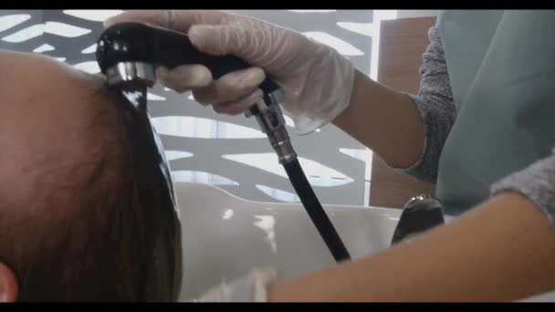 Cuidados com o cabelo no moderno Spa. mulher tendo cabelo lavado por cabeleireiro no salão de cabeleireiro. Mulher lavando o cabelo em um Spa.Spa tratamentos, centro de beleza. Barbeiro lava a cabeça de uma menina bonita — Vídeo de Stock