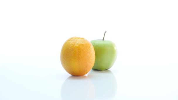 A narancs és a zöld alma. A gyümölcs lassan forog a fehér háttér
