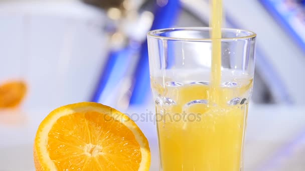 Orange juice pouring in glass on color background — Stock Video