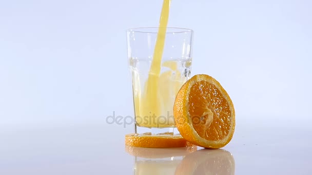 Jus d'orange versé dans le verre sur fond de couleur — Video