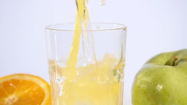 Orangen- und Apfelsaft im Glas auf farbigem Hintergrund — Stockvideo