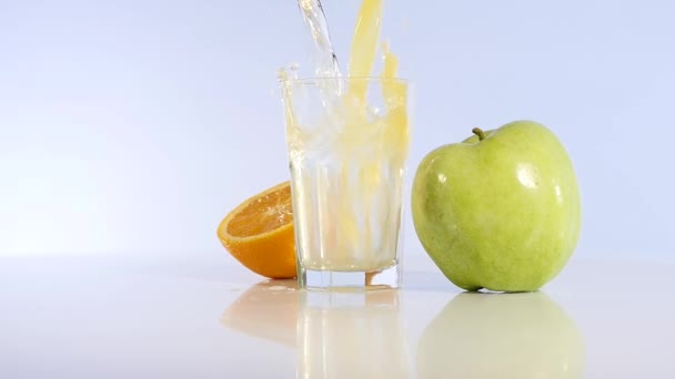 El jugo de manzana y la naranja se vierten en un vaso. Bebida de manzana. Manzana fresca — Vídeos de Stock