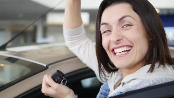 Lycklig kvinna visar nyckeln i sin nya bil. Bilbranschen, bil försäljning, teknik och människor koncept - glad hane med bilhandlare i auto visa eller salong — Stockvideo
