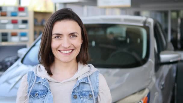 Mujer joven sosteniendo las llaves de coche nuevo auto y sonriendo a la cámara — Vídeos de Stock