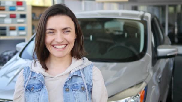 Mujer joven sosteniendo las llaves de coche nuevo auto y sonriendo a la cámara — Vídeo de stock