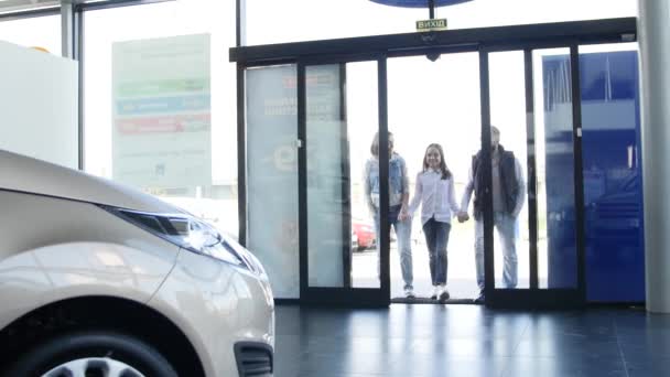 Familia joven entra en concesionario de coches para elegir el coche para comprarlo — Vídeo de stock