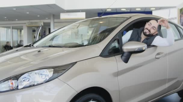 Happy man showing the key of his new car. Auto business, car sale, technology and people concept - happy male with car dealer in auto show or salon. Young man with a salesman in a motor show — Stock Video