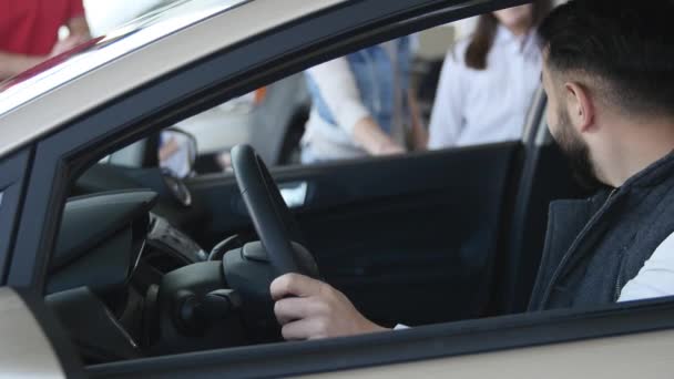 Gelukkige jonge familie zittend in een nieuwe auto samen bij de dealer — Stockvideo
