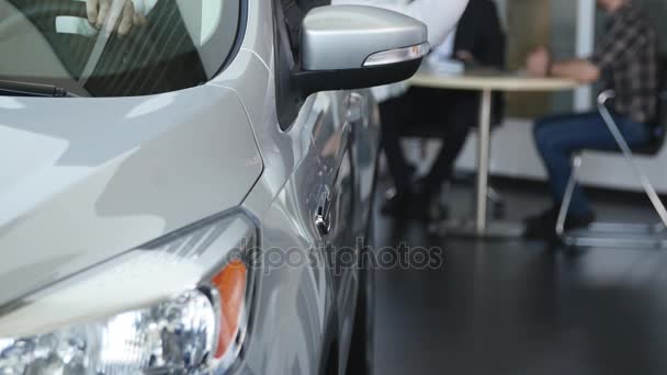 Visitez le showroom. Jeune homme obtient tenir les clés de voiture, en regardant la caméra et souriant, assis dans sa nouvelle voiture — Video