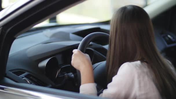 Vista lateral da linda menina olhando para longe e sorrindo enquanto sentada em um carro novo em um show de motor — Vídeo de Stock