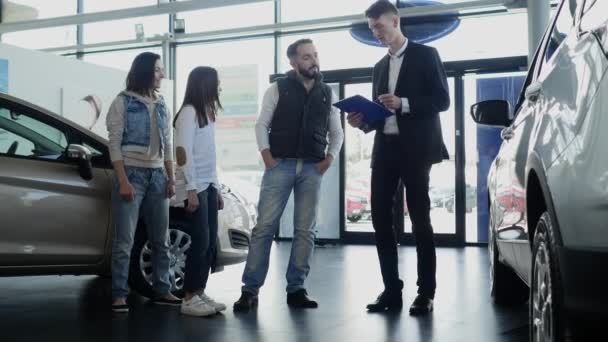 Продавец автомобилей показывает молодую семейную информацию об их новой машине — стоковое видео