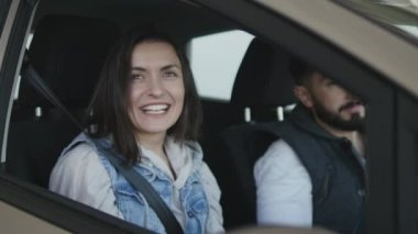 Yeni satın arabanın içinde otururken, etrafa ve penceresinde el sallayarak kadın