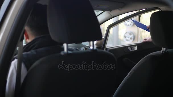 Joven sentado en coche y escuchando al vendedor en el centro de automóviles. parte posterior de la cámara — Vídeos de Stock