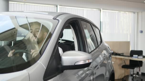 Ευτυχισμένος άνθρωπος που δείχνει το κλειδί του αυτοκινήτου του νέου. Επιχείρηση Auto, αυτοκίνητο πώληση, τεχνολογία και άνθρωποι έννοια - ευτυχής αρσενικό με έμπορος αυτοκινήτων στην εκπομπή auto ή το σαλόνι. Νεαρός άνδρας με ένα πωλητή σε μια επίδειξη μηχανών — Αρχείο Βίντεο