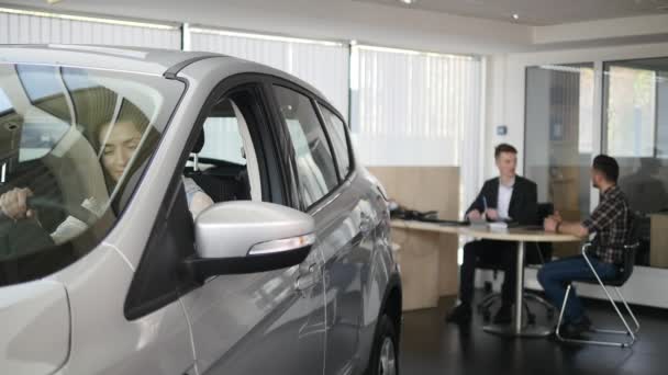 Donna felice che mostra la chiave della sua nuova auto. Auto business, vendita di auto, la tecnologia e il concetto di persone felice maschio con rivenditore di auto in salone o salone di auto — Video Stock