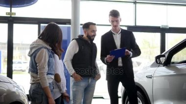 Araba satıcısı kendi yeni araç hakkında genç bir aile bilgi gösterir