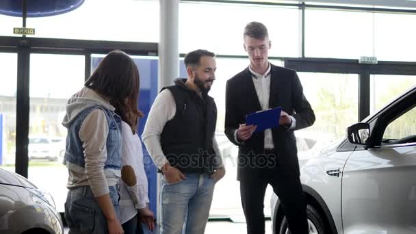 Venditore di auto mostra una giovane famiglia informazioni sulla loro nuova auto — Video Stock