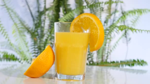 Rotación de zumo de naranja y naranja en la mesa — Vídeos de Stock