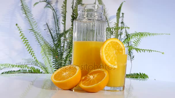 Χυμός πορτοκαλιού και πορτοκαλί περιστροφής στο τραπέζι — Αρχείο Βίντεο