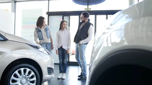 Familia joven entra en concesionario de coches para elegir el coche para comprarlo — Foto de Stock