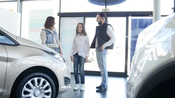 Jovem família entra em concessionária de carro para escolher o carro para comprá-lo — Fotografia de Stock