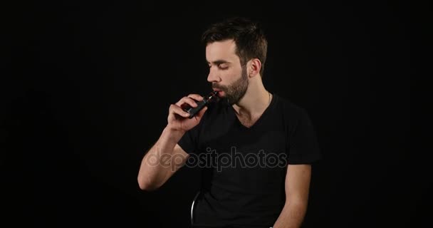 Joven vapeando con un cigarrillo electrónico y hacer algunas nubes de humo verde — Vídeos de Stock