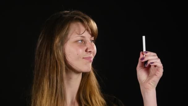 Mujer que decide entre cigarrillo electrónico o normal sobre fondo negro — Vídeo de stock