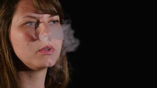 Giovane bella donna bruna fumare, vaping e-sigaretta con fumo su sfondo nero — Video Stock