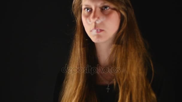 年轻美丽的黑发女人，吸烟，在黑色背景上的烟与雾电子烟 — 图库视频影像