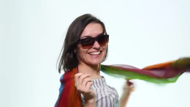 Довольно счастливая улыбающаяся женщина с поднятыми руками, играющая с красивым шелковым шарфом на белом фоне — стоковое видео