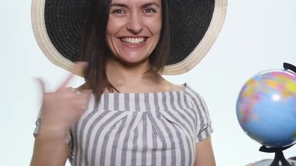 Женщина держит и указывает на глобус на белом фоне — стоковое видео