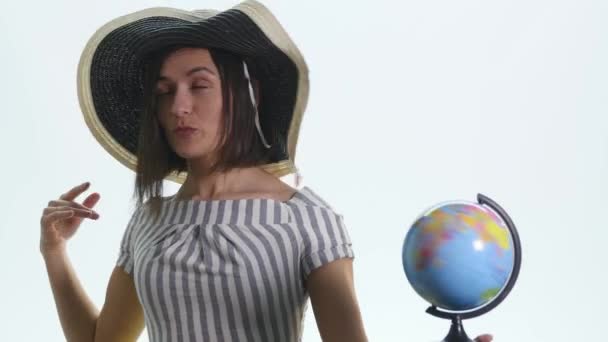 Молодая улыбающаяся девушка указывает на глобус на белом фоне — стоковое видео