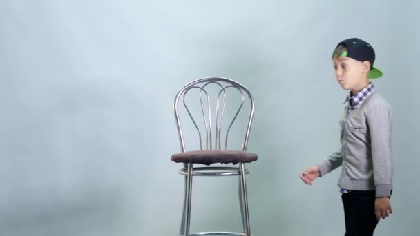 Menino sobe em uma cadeira alta e show class — Vídeo de Stock