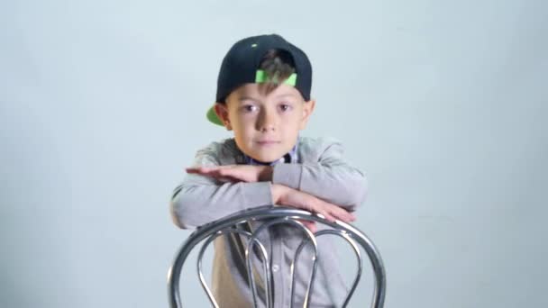 De jongen is zittend op een stoel en glimlachen — Stockvideo