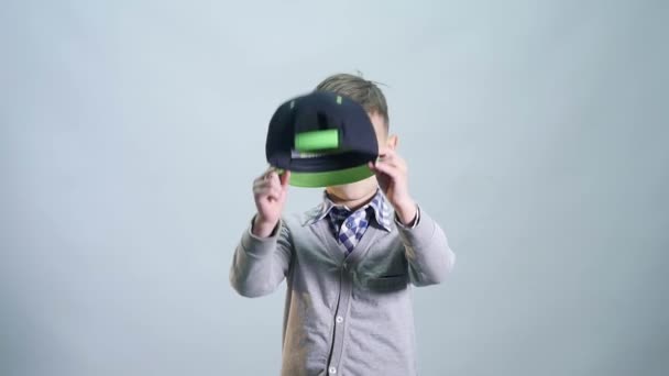 El niño se desplaza y se pone la gorra aislada sobre fondo blanco — Vídeos de Stock