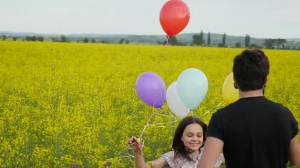 Raps fält. Vacker flicka i den blomstrande gula. Flicka i ett fält med filmare — Stockvideo