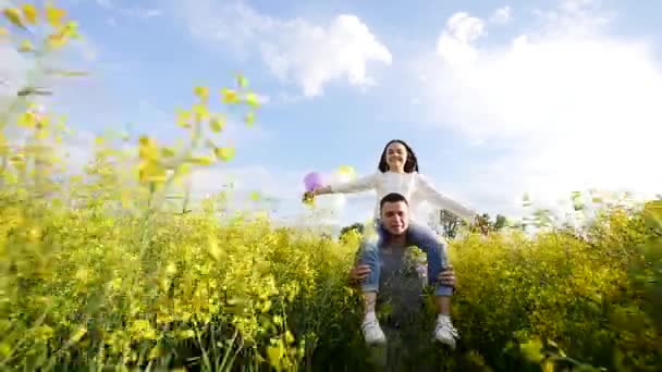 Mädchen mit Luftballons auf den Schultern des Typen, der bei der Vergewaltigung auf dem Feld rennt — Stockvideo