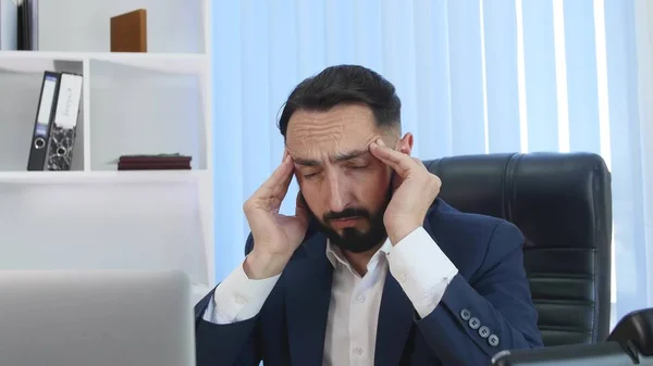 Молодой бизнесмен страдает головной болью во время работы в офисе — стоковое фото