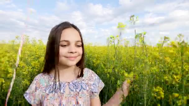 Μικρό κορίτσι σε ένα φόρεμα που διατρέχει πεδίο κίτρινο σιτάρι με μπαλόνια στο χέρι. αργές κινήσεις — Αρχείο Βίντεο
