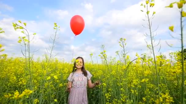 Flicka som står i fältet och releaser ballonger i skyn — Stockvideo