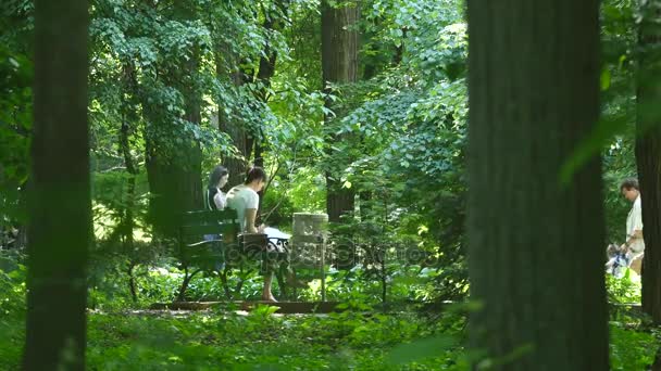 Una joven sentada en un banco de madera en el parque. estudiante chica leyendo el libro — Vídeo de stock