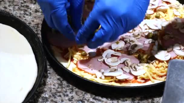 Cuire dans la cuisine en mettant les ingrédients sur la pizza. Concept de pizza. Production et livraison de denrées alimentaires — Video