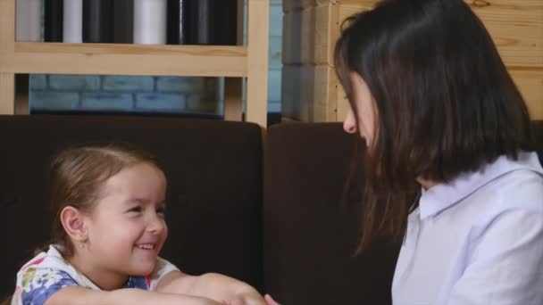 Ομορφη ευτυχισμένη μητέρα αγκαλιάζει κοριτσάκι με αγάπη σε ένα καφέ — Αρχείο Βίντεο