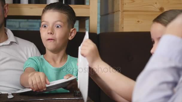 Cute kids boy and girl play together sitting at cafe table — Stock Video