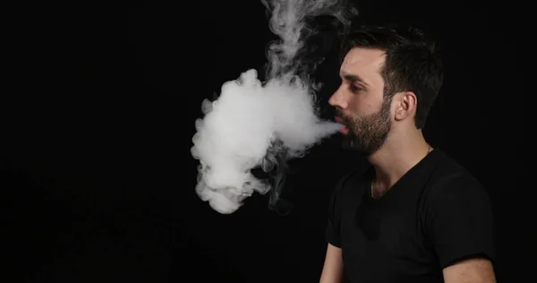 Homem decidir entre cigarro eletrônico ou normal em fundo preto — Fotografia de Stock