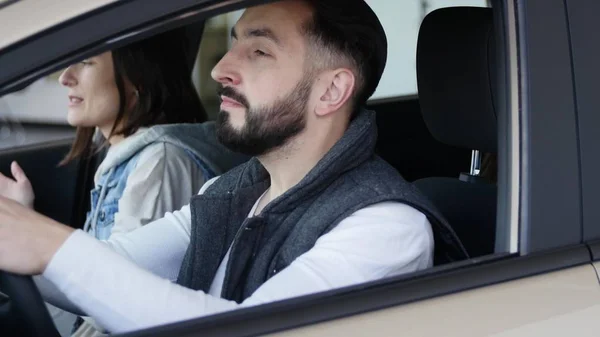 A visitar a concessionária de carros. Bela família está falando e sorrindo enquanto está sentado em seu carro novo. jovem mostra dedo para cima — Fotografia de Stock